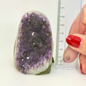 Ametyst krystal rå grotte klynge sten i hånd lineal på hvid baggrund