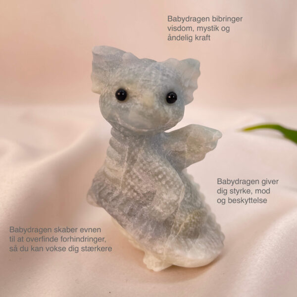 Blå Calsit krystal babydrage på hvid baggrund med grønt blad med tags