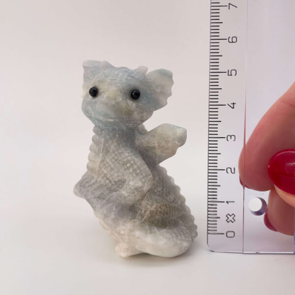 Blå Calsit krystal babydrage ved siden af lineal på hvid baggrund