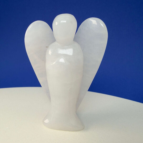 Hvid kvarts krystal engel på hvid plade med blå baggrund