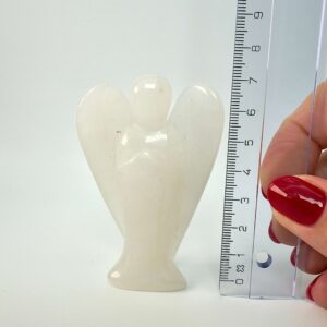 Hvid kvarts krystal engel ved siden af lineal på hvid baggrund