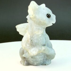 Labradorit krystal babydrage fra siden på hvid plade med sort baggrund