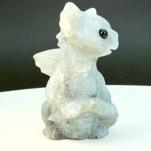 Labradorit krystal babydrage fra siden på hvid plade med sort baggrund