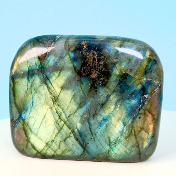 Labradorit krystal freeform støtte på hvid plade med blå baggrund