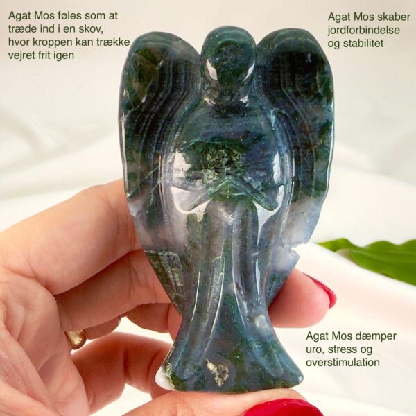 Agat mos krystal engel mellem fingre på hvid baggrund med grønt blad med tags