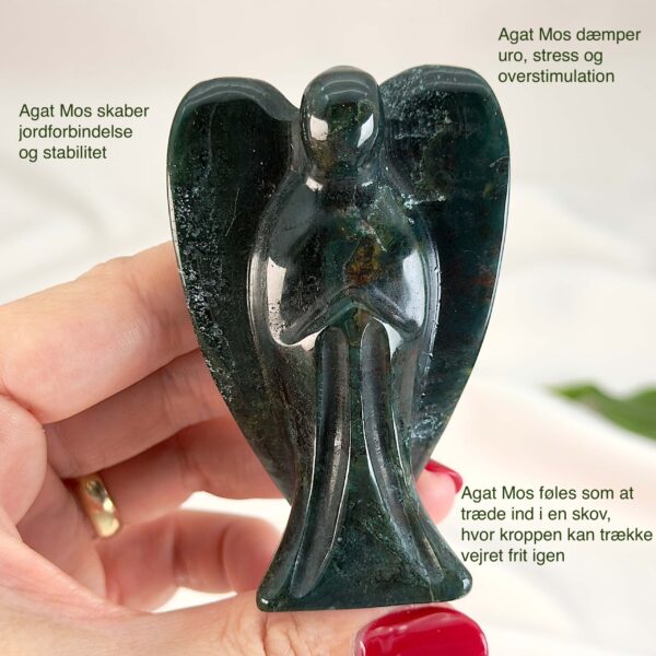 Agat mos krystal engel mellem fingre på hvid baggrund med grønt blad med tags