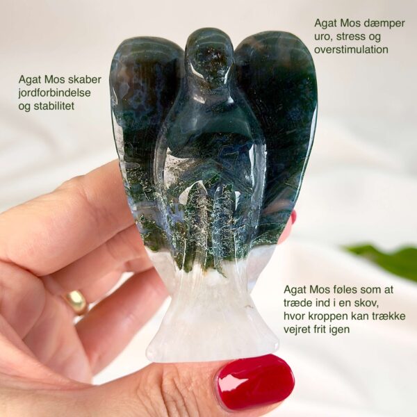 Agat mos krystal engel mellem fingre på hvid baggrund med grønt blad med tags