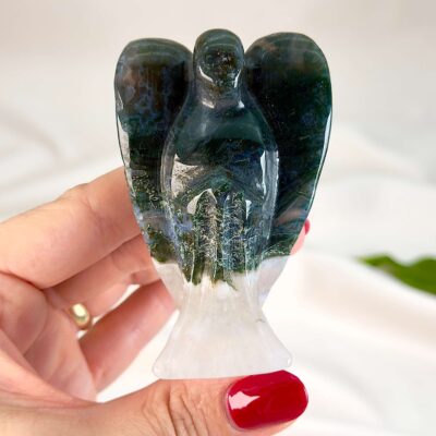 Agat mos krystal engel mellem fingre på hvid baggrund med grønt blad