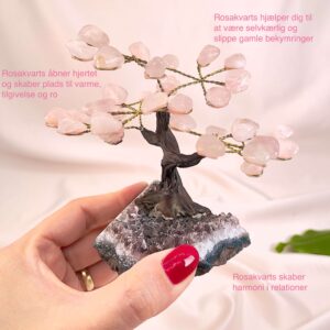 Rosakvarts træ på krystal bund i hånd med lys baggrund og grønt blad med tags
