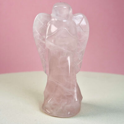 Rosakvarts krystal engel på hvid plade med lyserød baggrund