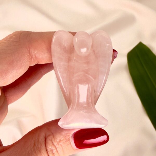 Rosakvarts 4 cmkrystal engel imellem fingre med hvid baggrund og grønt blad