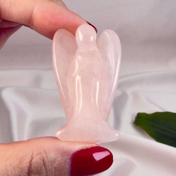 Rosakvarts 4 cmkrystal engel imellem fingre med hvid baggrund og grønt blad