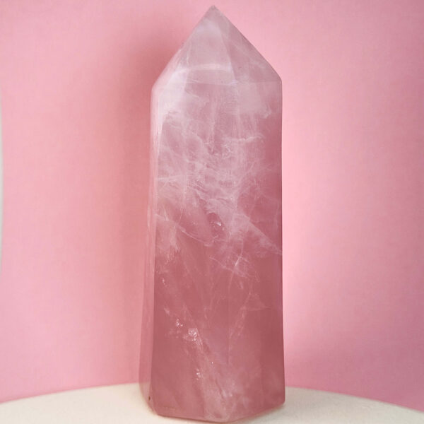 Rosakvarts krystal tårn på hvid plade med lyserød baggrund