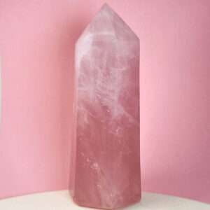 Rosakvarts krystal tårn på hvid plade med lyserød baggrund