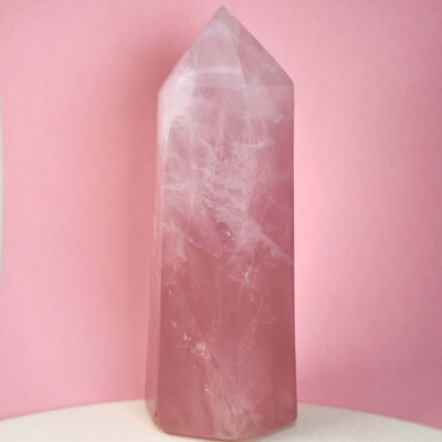 Rosakvarts krystal tårn på hvid plade med lyserød baggrund