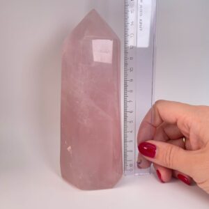 Rosakvarts krystal tårn ved siden af lineal på hvid baggrund