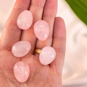 Rosakvarts mini æg i hånd med blad i baggrunden