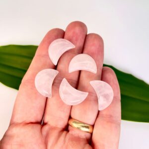 Rosakvarts mini måner på hånd med blad i baggrunden