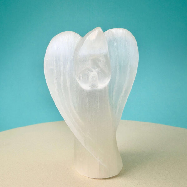 Selenit krystal engel på hvid plade med blå baggrund