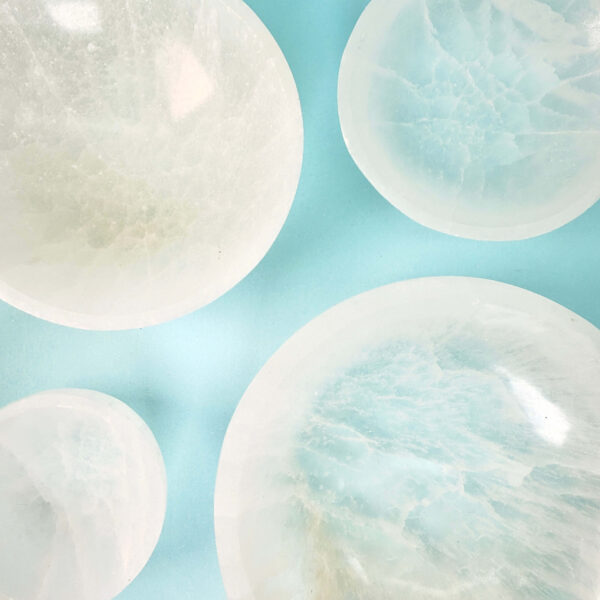 Selenit krystal fire skåle i forskellige størrelser på blå baggrund