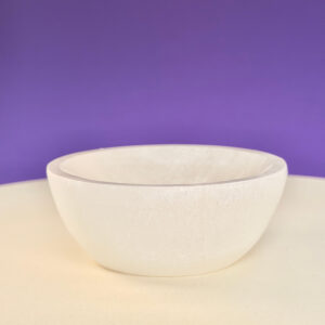 Selenit skål krystal sten 10 cm på hvid plade med lilla baggrund