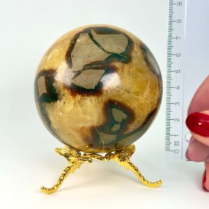 Septarie krystal kugle ved siden af lineal på hvid baggrund