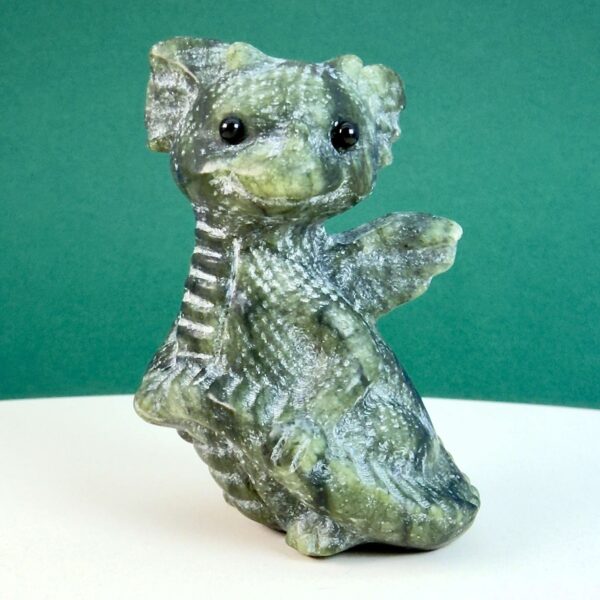 Serpentin krystal babydrage på hvid plade med grøn baggrund