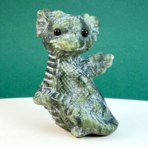 Serpentin krystal babydrage på hvid plade med grøn baggrund