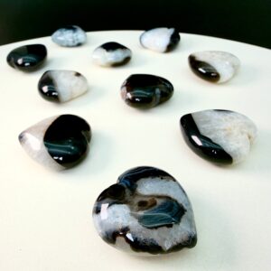 Sort agat krystal hjerte på hvid plade med sort baggrund skrå