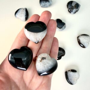 Sort agat krystal hjerte i hånd på hvid plade