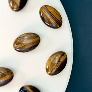 Tigerøje krystal håndsten på hvid plade med sort baggrund