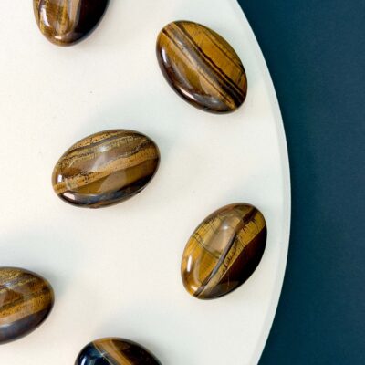 Tigerøje krystal håndsten på hvid plade med sort baggrund