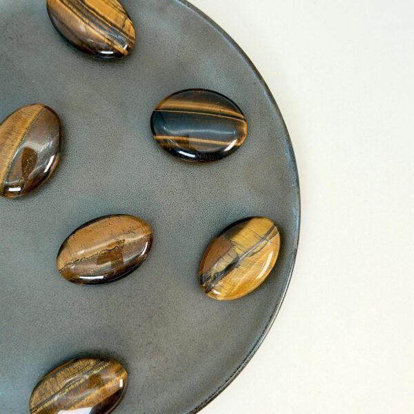 Tigerøje krystal håndsten på brun plade med hvid baggrund