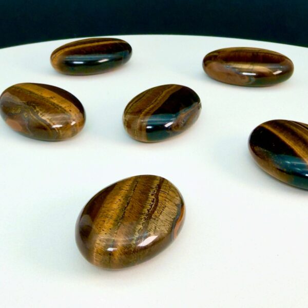 Tigerøje krystal håndsten på hvid plade med sort baggrund skrå