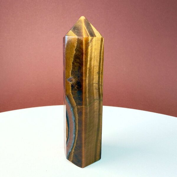 Tigerøje krystal tårn på hvid plade med mørk baggrund