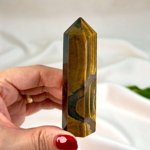 Tigerøje krystal tårn på hvid baggrund med grønt blad