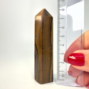 Tigerøje krystal tårn ved siden af lineal på hvid baggrund