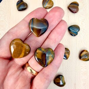 Tigerøje mini krystal hjerter på hånd med hvid baggrund