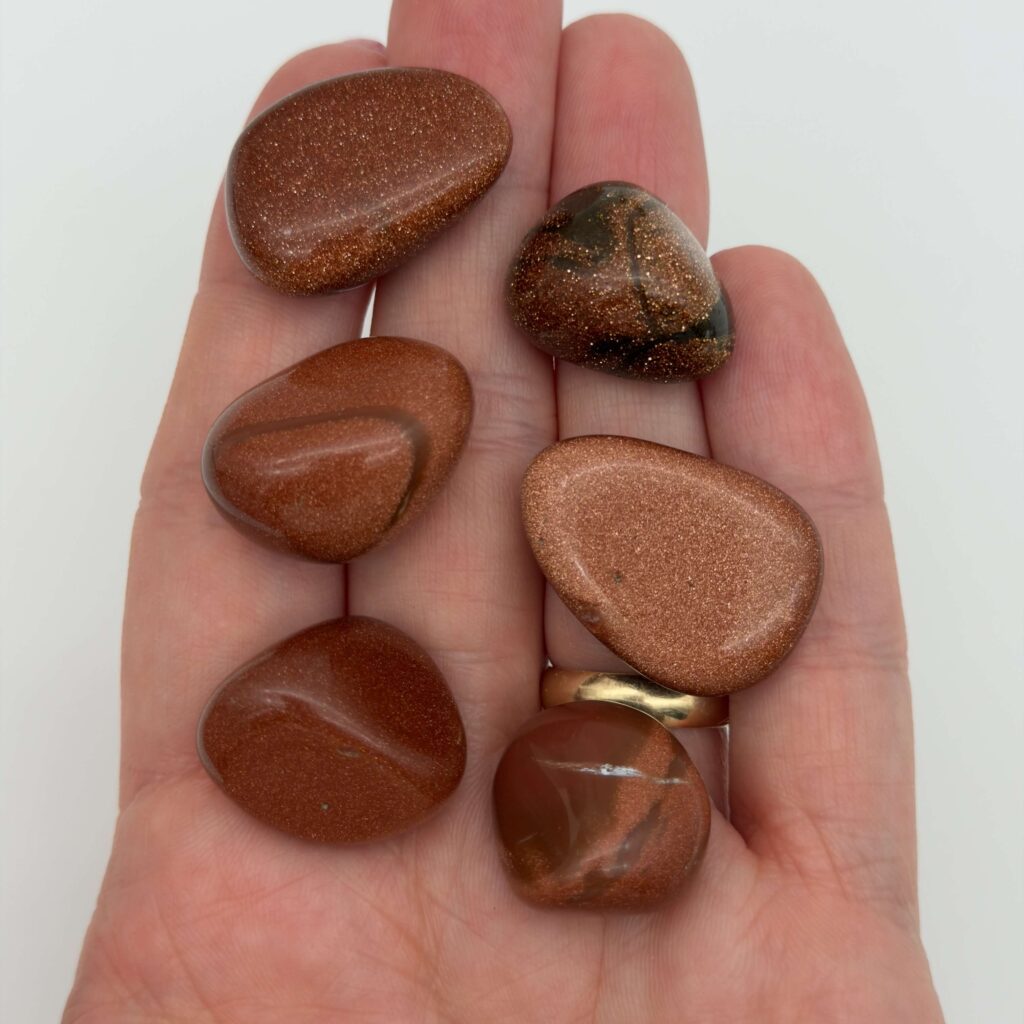 Guldsten krystal i hånd med hvid baggrund