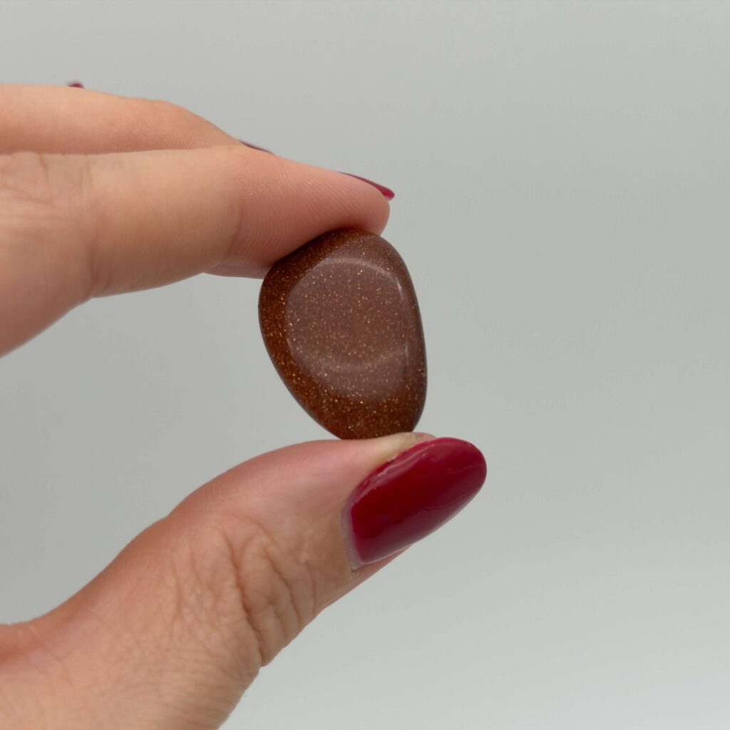 Guldsten krystal i hånd med hvid baggrund