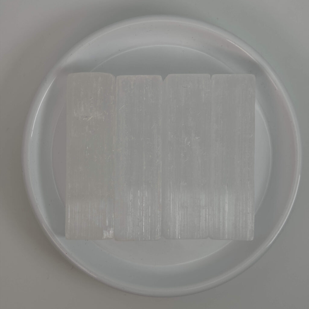 Selenit krystal i hvidt fad med hvid bagggrund