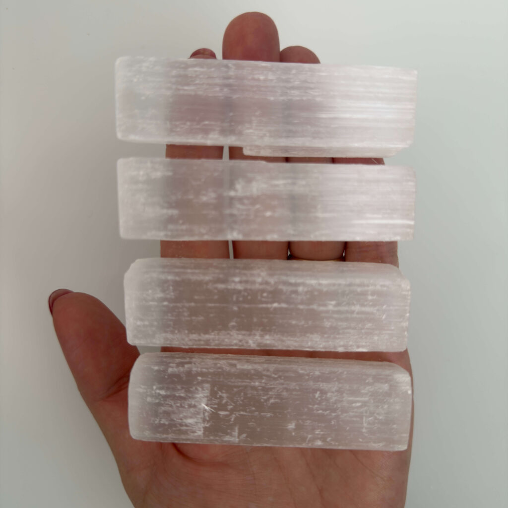 Selenit krystal i hånd med hvid baggrund