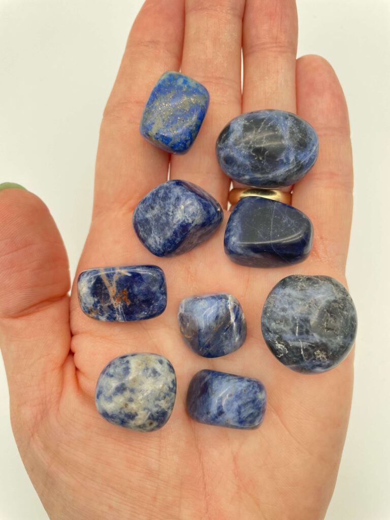 Sodalit krystal i hånd med hvid baggrund