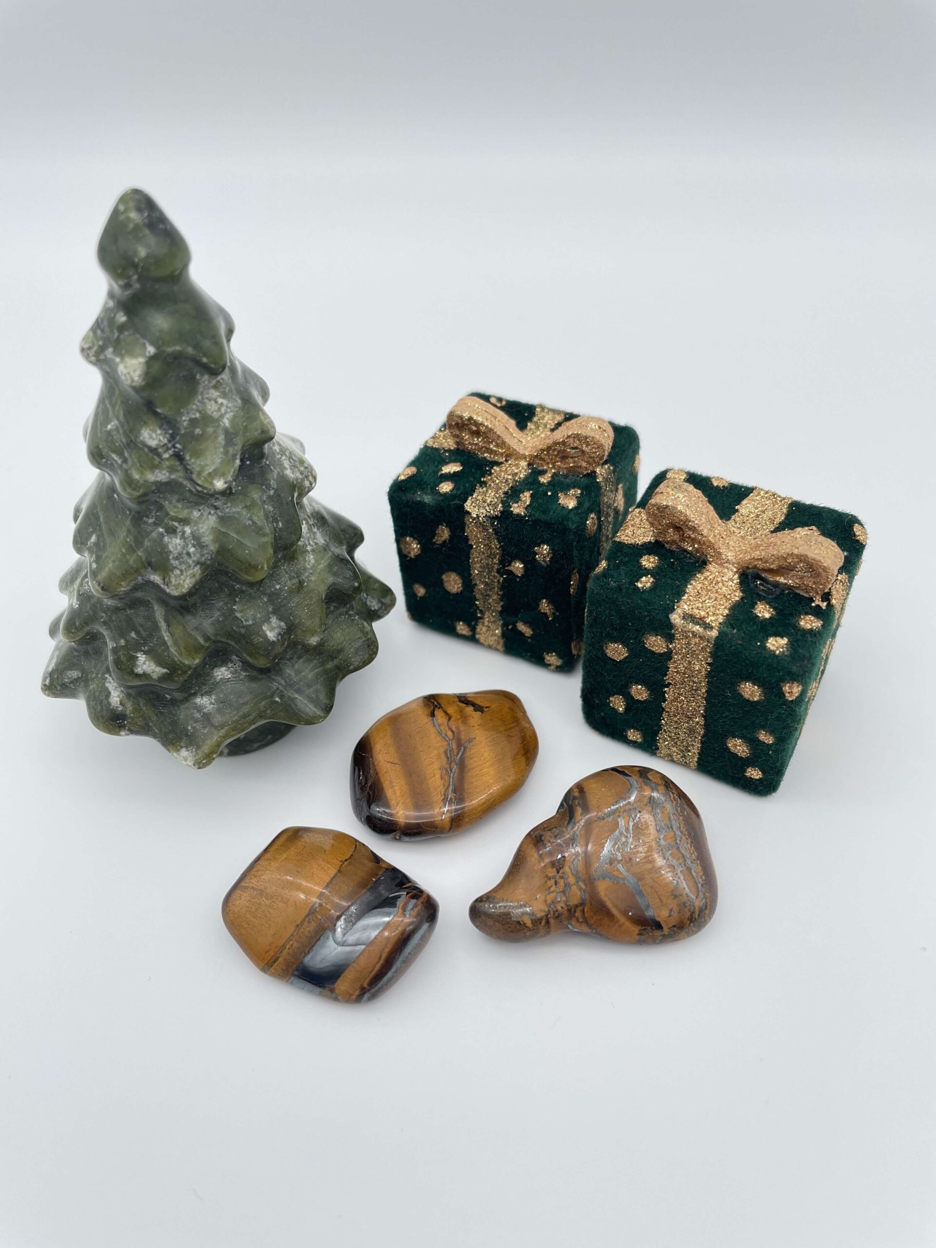 Tigerøje krystal ved juletræ og gaver på hvid baggrund