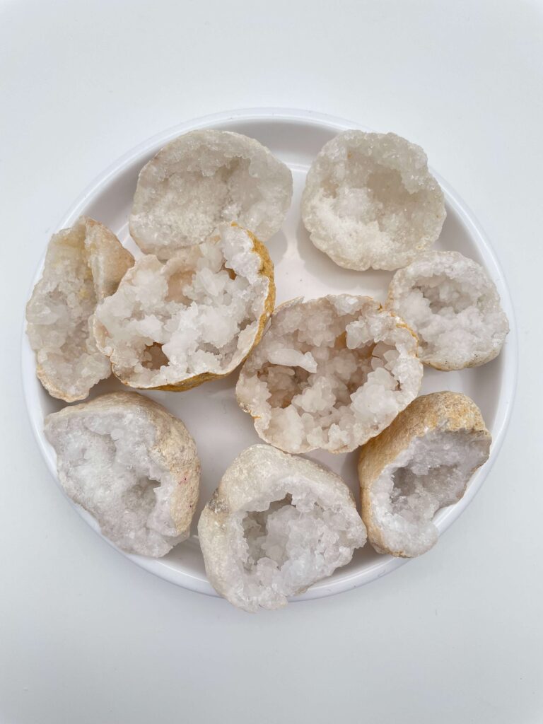 Bjergkrystal geode krystal i hvidt fad med hvid bagggrund