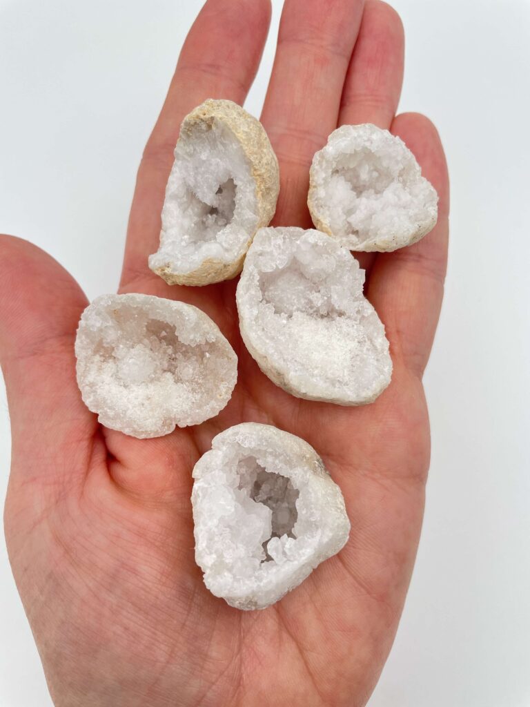 Bjergkrystal geode krystal i hånd med hvid baggrund