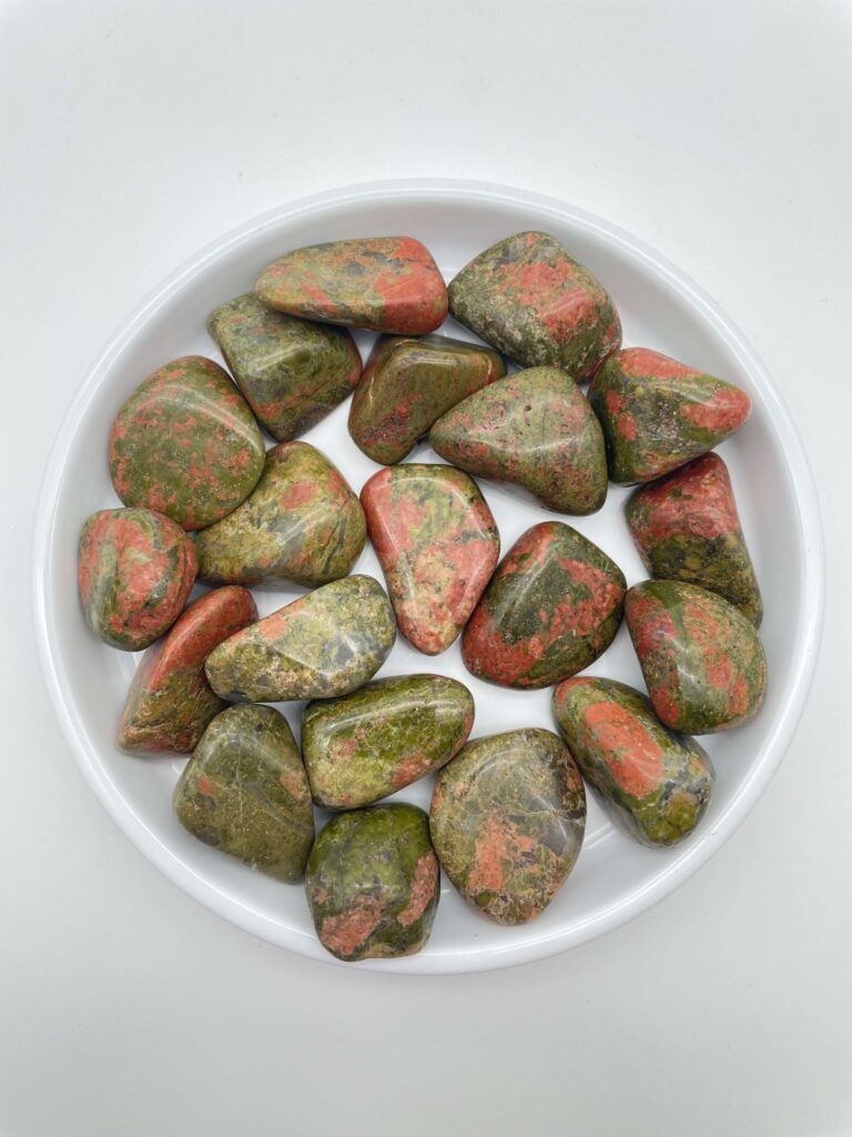 unakit krystal lommesten i hvidt fad med hvid bagggrund