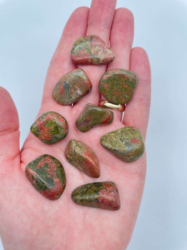 unakit krystal lommesten i hånd med hvid baggrund