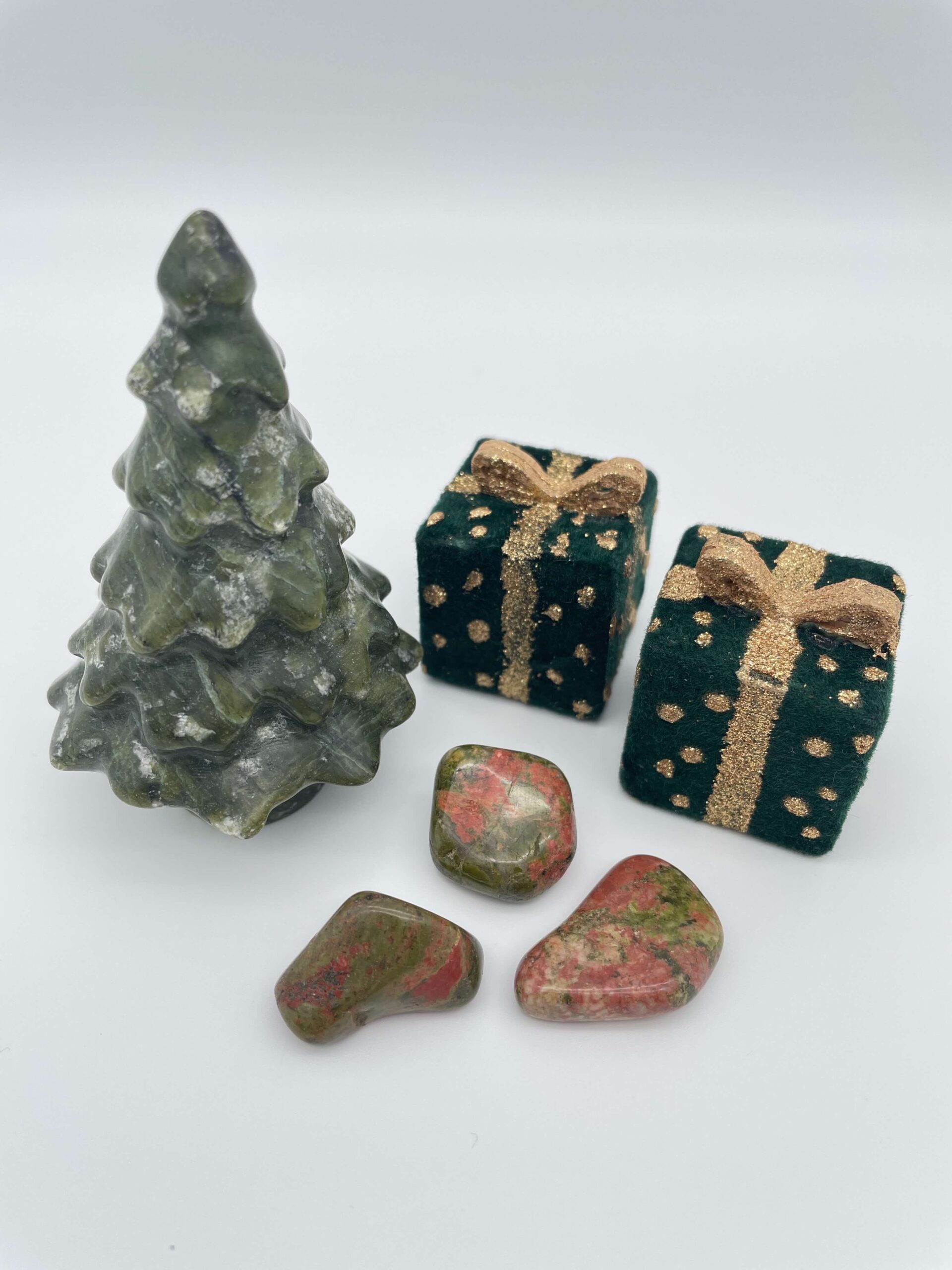 unakit krystal lommesten ved juletræ og gaver på hvid baggrund