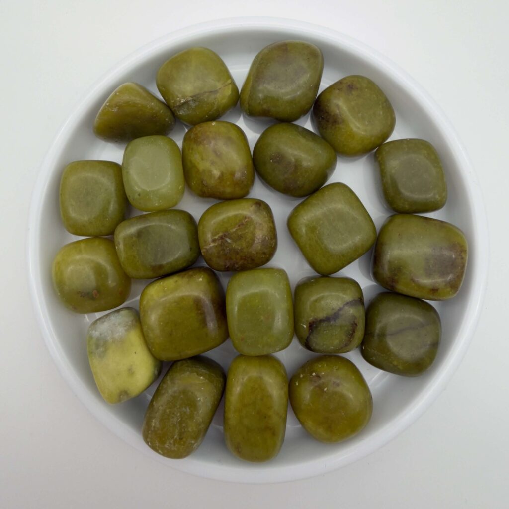 serpentin gul krystal i hvidt fad med hvid bagggrund